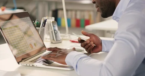 Man typing on laptop and using phone in a startup office - track left. Stock Footage 92166103