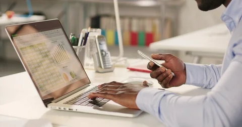 Man typing on laptop and using phone in a startup office. Stock Footage 92166139