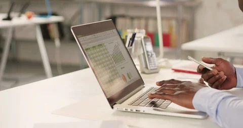 Man typing on laptop and using phone in a startup office - track right. Stock Footage 92166308