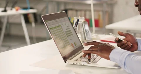 Man typing on laptop and using phone in a startup office - track right. Stock Footage 92166499