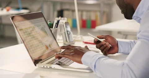 Man typing on laptop and using phone in a startup office - track left. Stock Footage 92166523