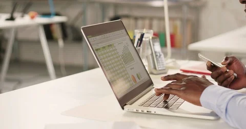 Man typing on laptop and using phone in a startup office - track right. Stock Footage 92166670