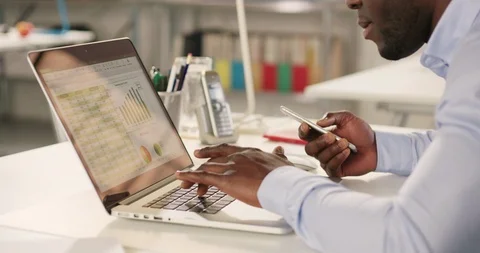 Man typing on laptop and using phone in a startup office - track left. Stock Footage 92166766