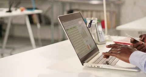 Man typing on laptop and using phone in a startup office - track right. Stock Footage 92166916