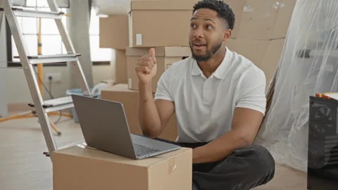 Man typing on laptop atop moving box with hand pointing gesture inside buil.. Stock Footage 337438778