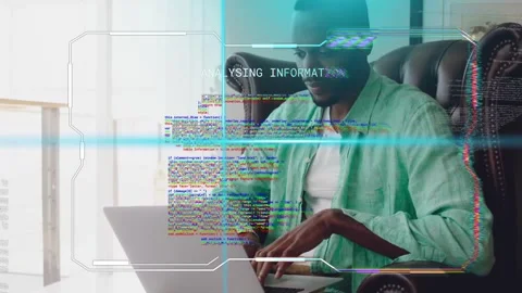 Man typing on laptop in chair by window, glitching HUD appearing around laptop Stock Footage 333221204