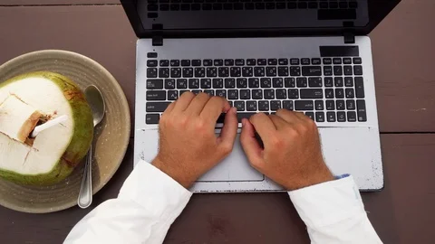 Man Typing on Laptop with Coconut while Traveling. Digital Nomad in Thailand Stock Footage 107084224