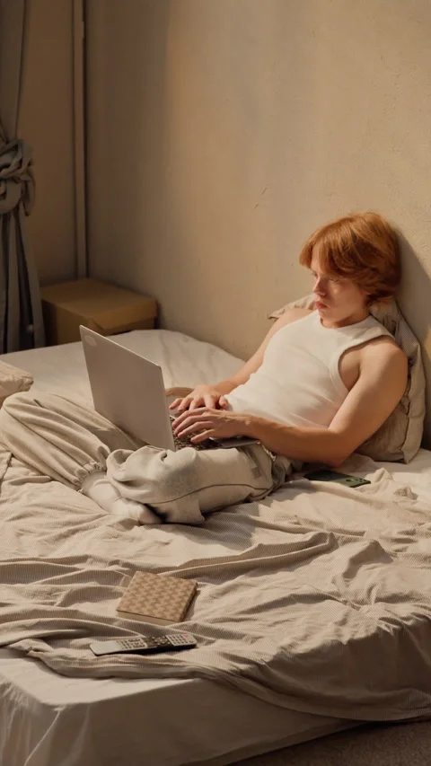 Man Typing on Laptop Computer for Remote Work in Bedroom Stock Footage 346602327