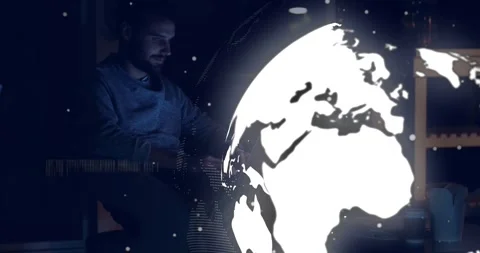 Man typing on laptop in dim tech office causing globe overlay casting code for Stock Footage 331235784