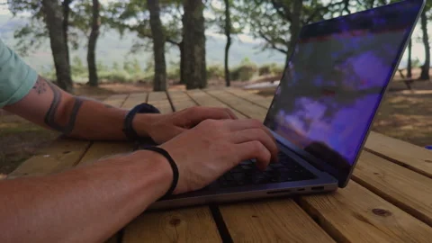 Man Typing on Laptop with Forest Reflection on Screen Outdoors Stock Footage 346389111