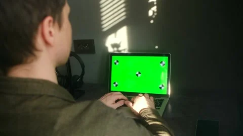 Man typing on a laptop with a green screen at his desk Vídeo Stock 337827207