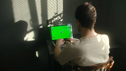 Man typing on a laptop with green screen at home office Видео 337831185