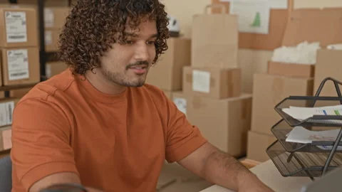 Man typing on laptop with hands on keyboard amid stacked cardboard boxes, p.. Stock Footage 337402473