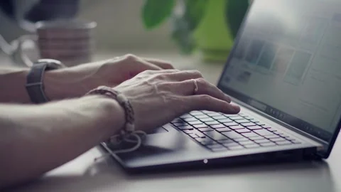 Man typing on laptop keyboard working at home in front of a window Stock Footage 272196926