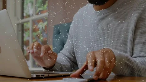 Man typing on laptop, picking up smartphone while network overlay linking Stock Footage 332936925