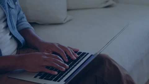 Man typing on laptop on sofa for tech work, initiating animated shapes while Stock Footage 334466162
