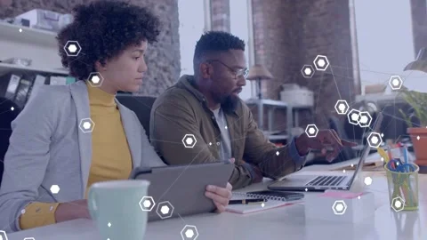 Man typing on laptop then pointing, woman holding tablet reviewing business data Stock Footage 333975848