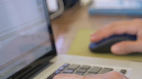 Man typing on a laptop using keyboard and mouse while working on a spreadsheet Video stock 60947761