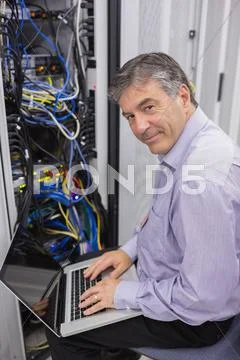 Man typing on laptop while doing server maintenance Stock Photos