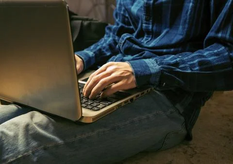 A man is typing on a laptop while sitting on the couch Stock Photos
