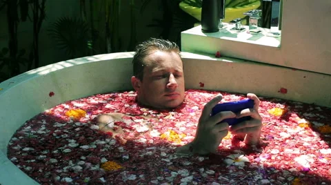 Man typing message on cellphone and lying in the bath Stock Footage 40331714