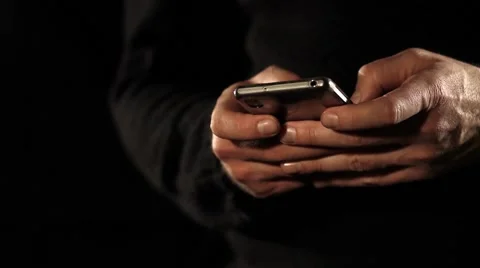 A man typing a message on his mobile phone, isolated on a black background Stock Footage 59823781