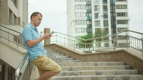 Man typing a message in a mobile phone while standing on the stairs Stock Footage 152740022