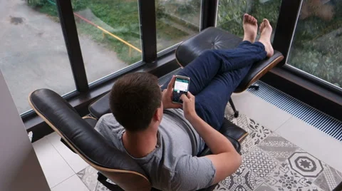 Man typing a message sitting on armchair terrace Vídeos de archivo 66441501