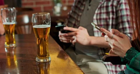 Man is typing a message on a smartphone in a bar while a glass of beer is Stock Footage 156567409