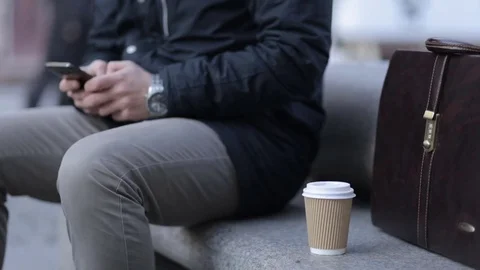 A man is typing a message on a smartphone. Hands close-up. Paper cup of coffee. Stock Footage 69879887