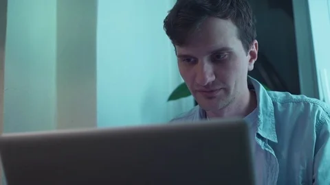 Man typing on notebook computer sitting near window Video stock 83871191