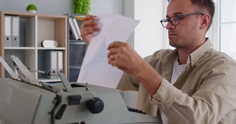 Man typing on old typewriter, writer holding paper from old machine to read text Stock Footage 329288666