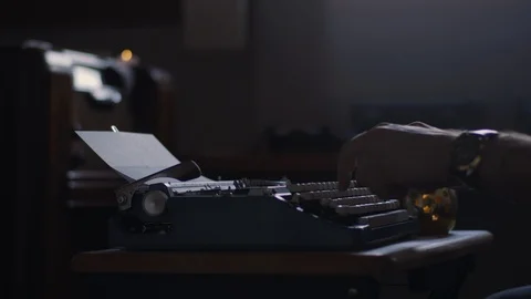 Man typing on an old vintage typewriter in a moody lit office Stock Footage 97876063