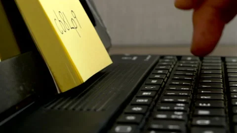 Man typing a password from a notepad on a portable keyboard. Stock Footage 156399873