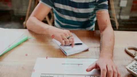 Man typing, pausing to reach pen, taking notes at business desk, animations over Stock Footage 335282109