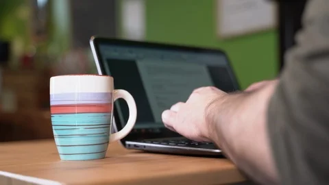 Man typing on pc while drinking a hot drink Stock Footage 124141438