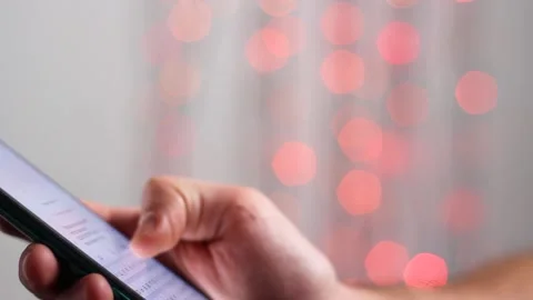 Man is typing SMS on mobile phone against the background of New Year's lights. Stock Footage 143003557
