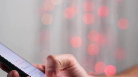 Man is typing SMS on mobile phone against the background of New Year's lights. Stock Footage 143588522