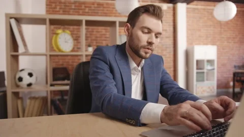 A man is typing something on a laptop, then documents are brought to him Stockbeeldmateriaal 188790003