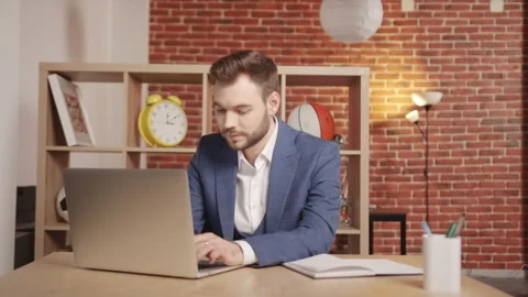 A man is typing something into a laptop then looks into the frame and smiles. Stock-Footage 194363547