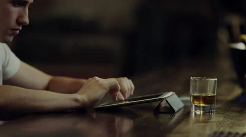Man typing on a tablet at a bar counter Stock Footage 67884703
