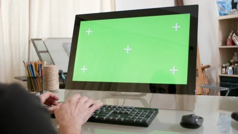 Man typing a text on his keyboard with a green screen on his monitor Stock Footage 105702668
