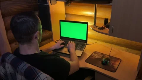 A man is typing text on a laptop with a green monitor Stock Footage 263215861
