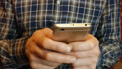 Man typing a text message or downloading an app for his mobile phone Stock Footage 193020547