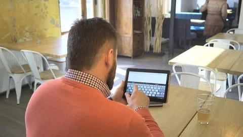 Man typing, writing on tablet computer, in cafe, close behind shot, rear view 動画素材 73293275