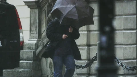 Man With an Umbrella Walking Down the Street in the Rain Stock Footage 122955655