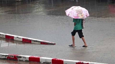 A man with an umbrella walks through a puddle Stock Footage 239964390
