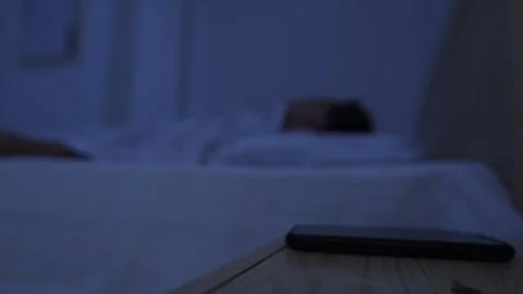 Man unable to fall asleep after putting smartphone away, picks it up again and Stock-Footage 346250584