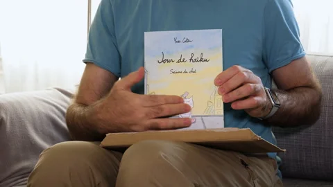 Man Unboxing Amazon Book on Couch Stock Footage 308449036