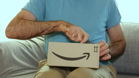 Man Unboxing Amazon Prime Package on Sofa Stock Footage 304620131